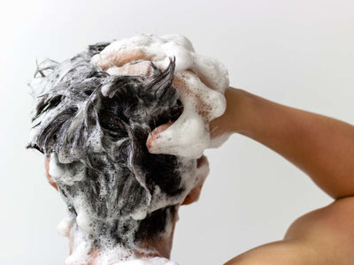 Close-up of a man washing his hair with shampoo, representing the hair regrowth journey for Filipino men and what to expect over time.